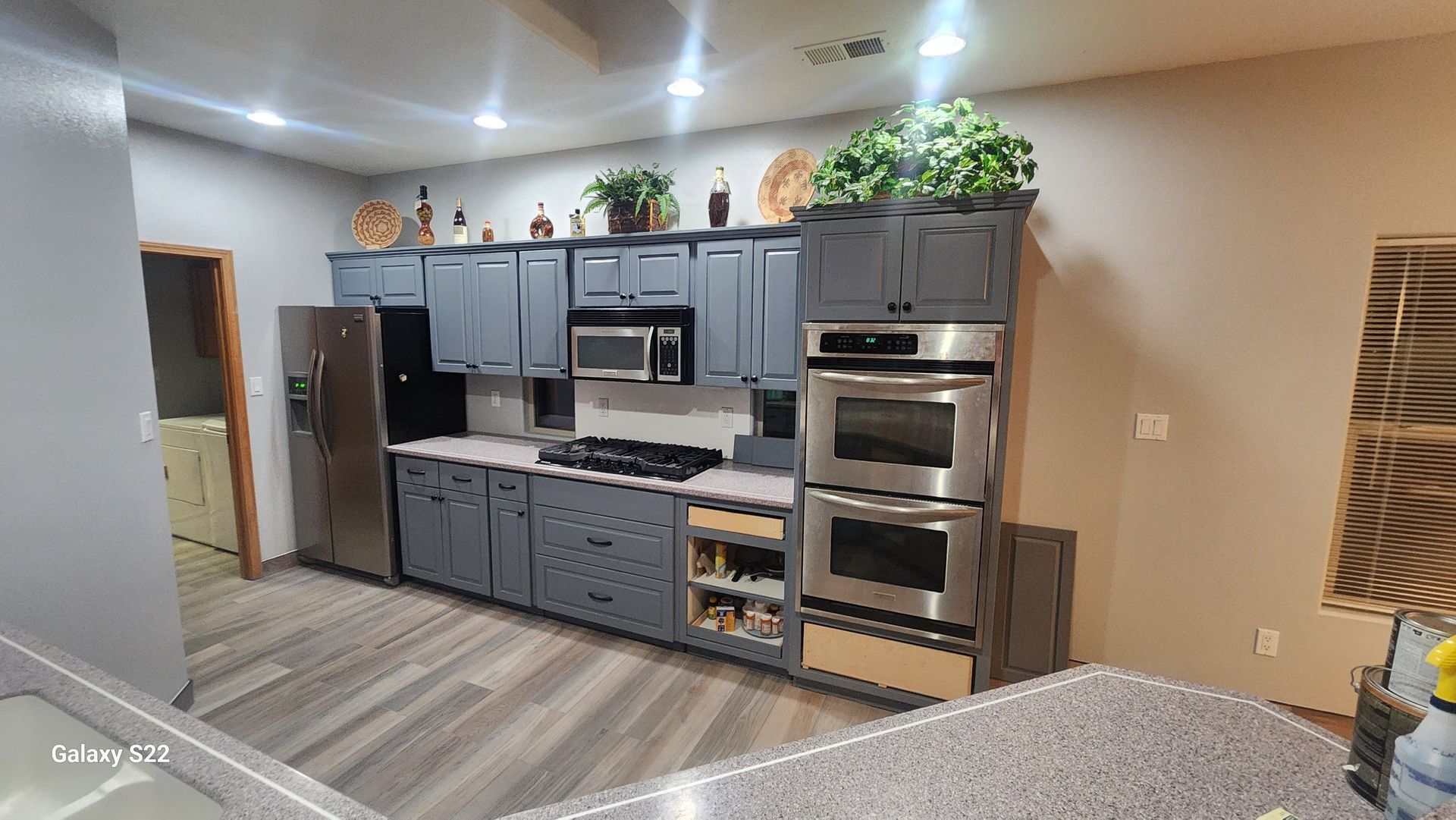 Gray kitchen with stainless steel appliances and cabinets, light-colored countertops, and wood-look flooring.