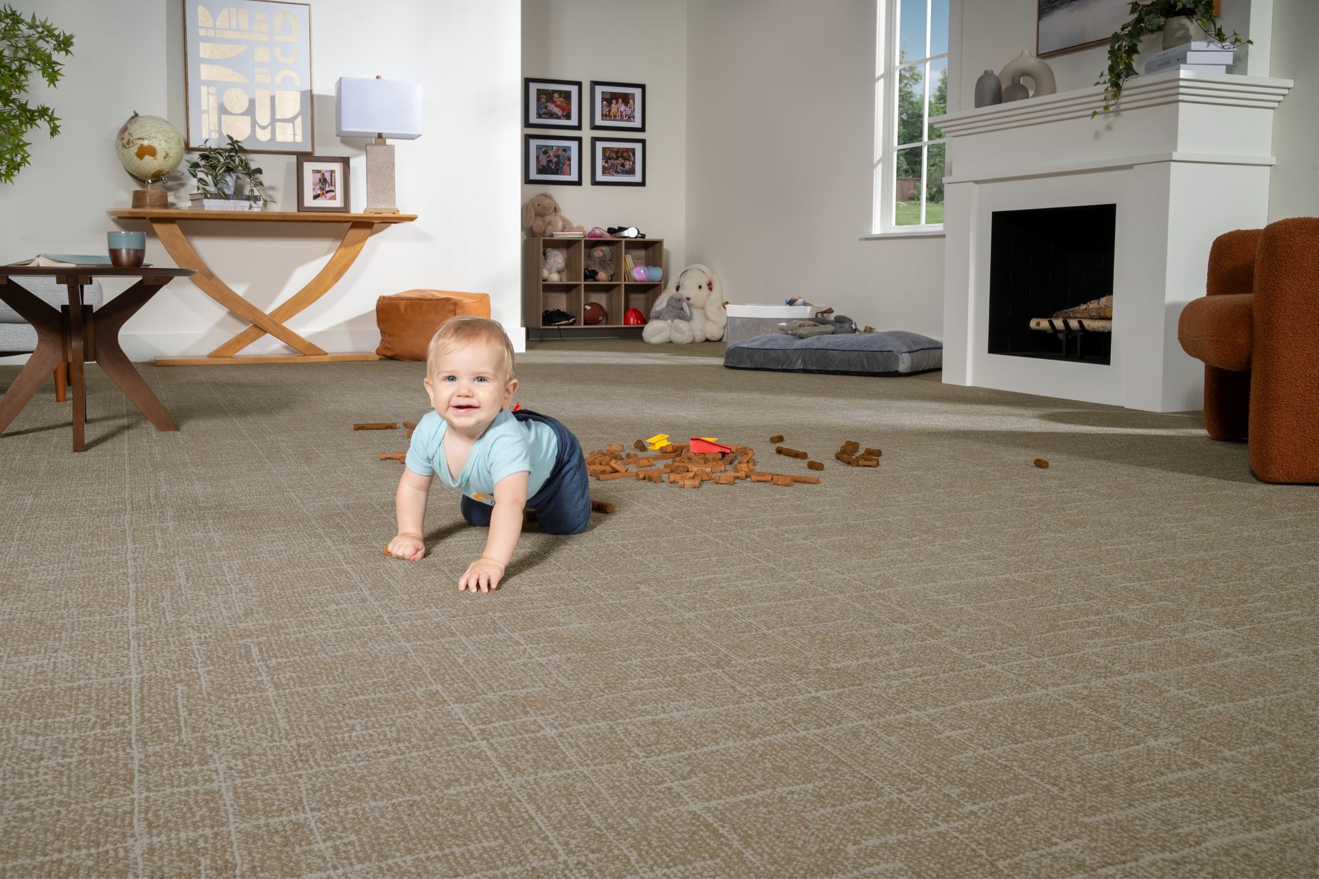 Baby crawling on a carpeted living room floor with toys scattered nearby.