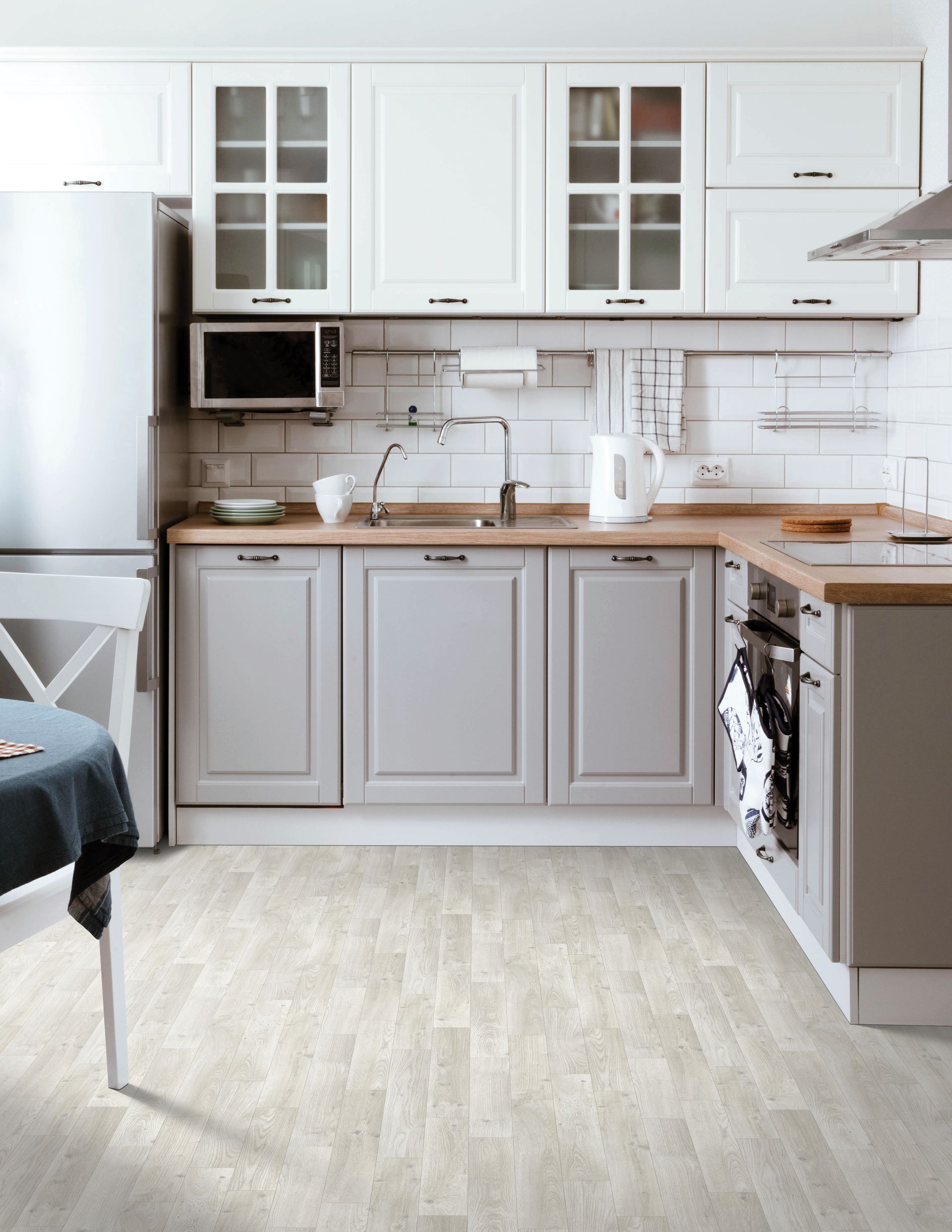 Modern white kitchen with gray cabinets, wood countertops, and tiled backsplash