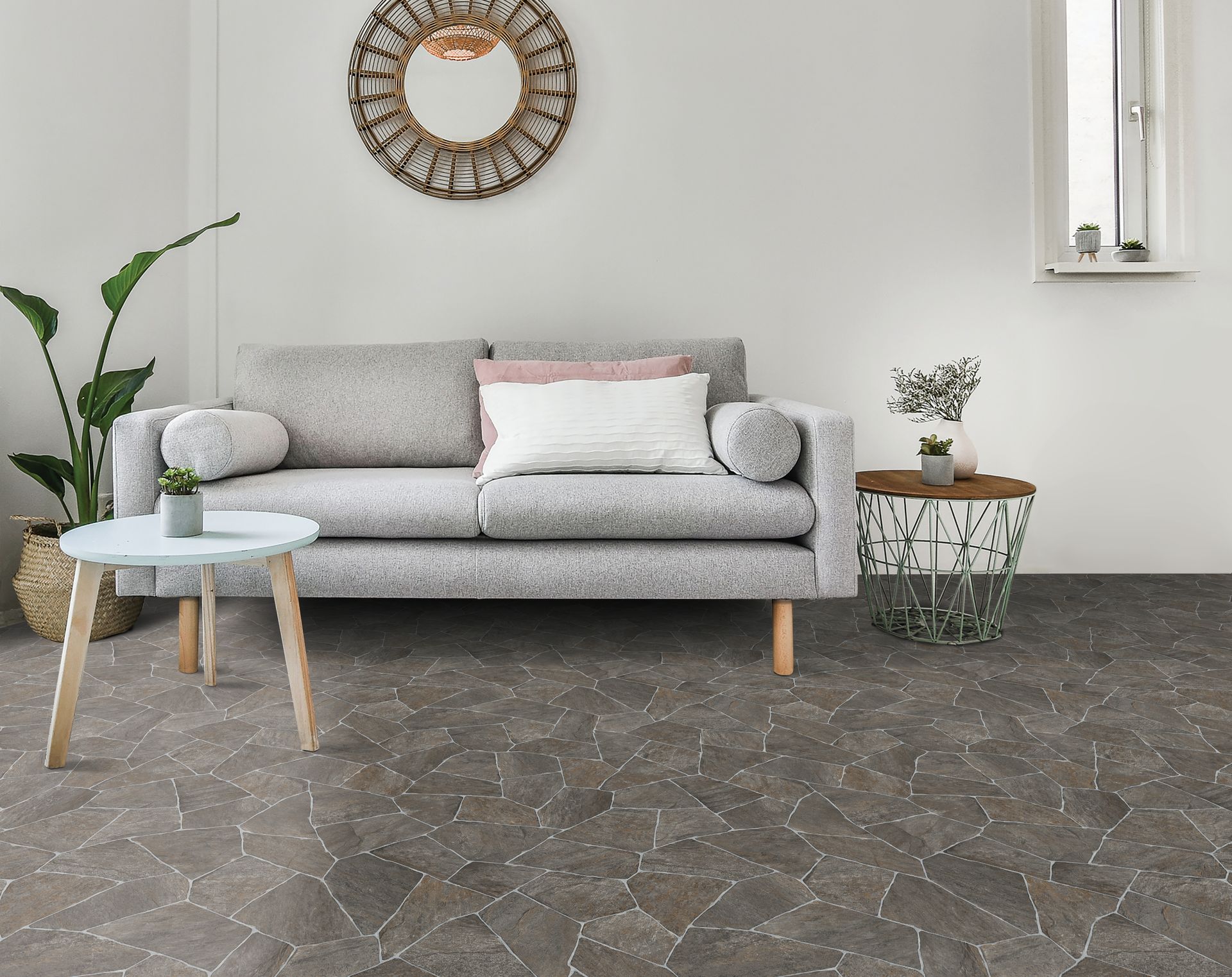 Minimalist living room with gray sofa, woven wall decor, small side table, and patterned dark rug