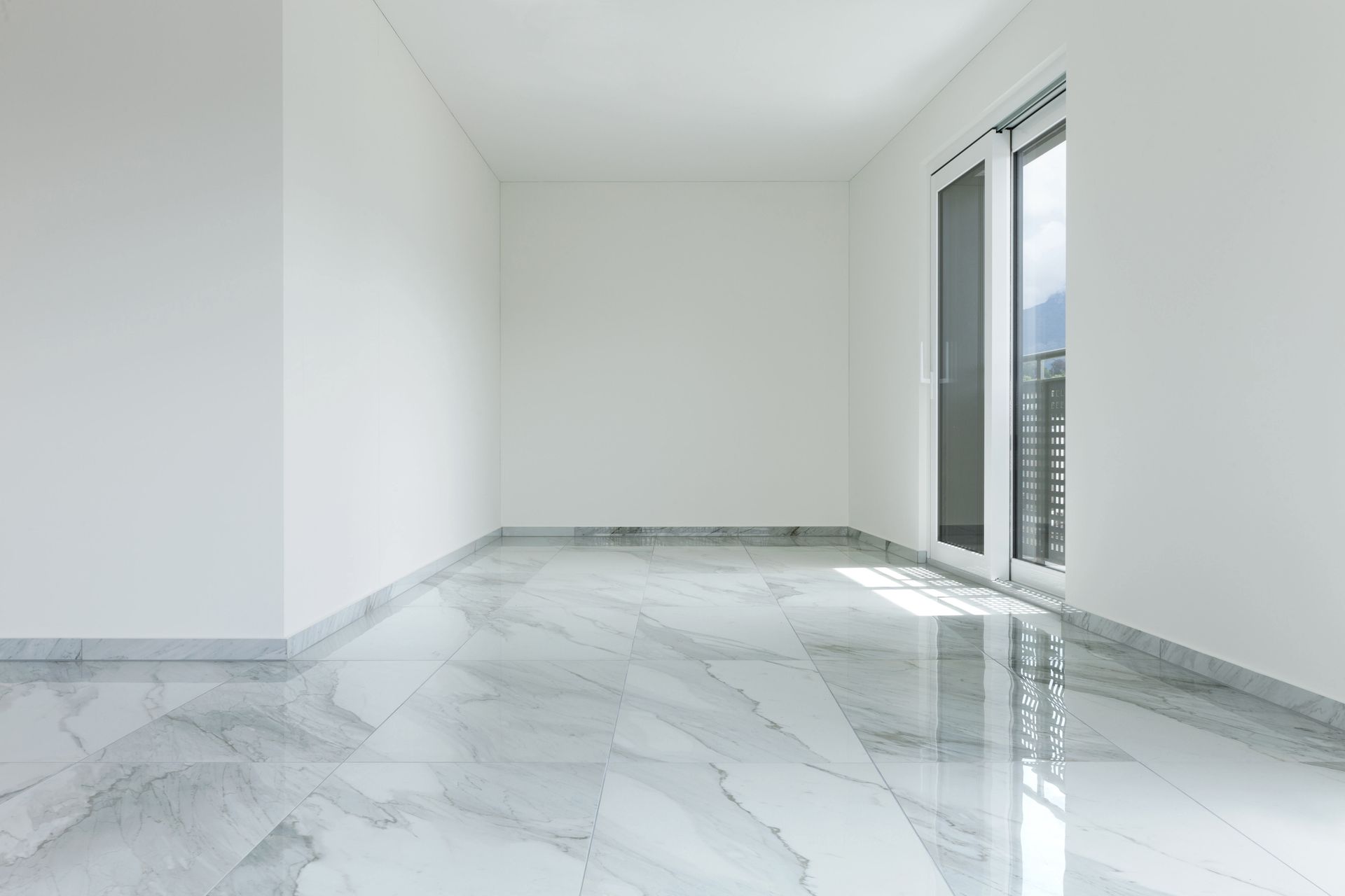 Empty bright room with white walls, glossy marble floor, and tall windows.