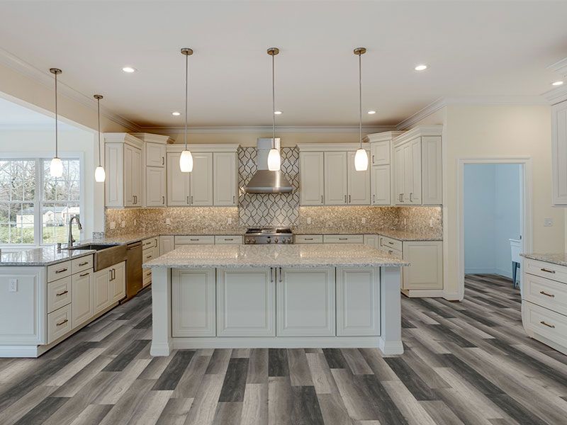 Stacked light wood flooring planks laid out over a gray concrete floor to show a transition installation pattern