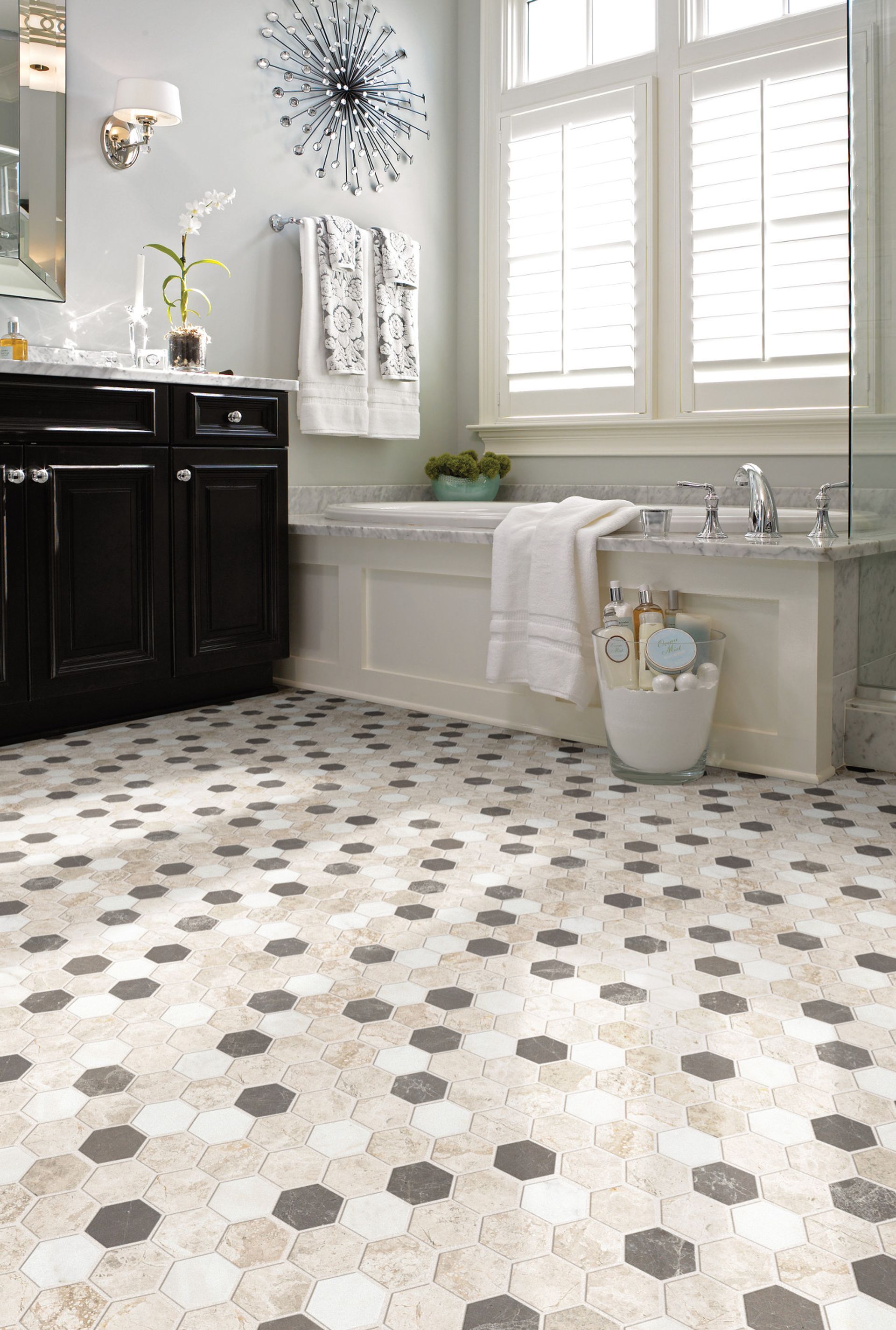 Bright bathroom with black vanity, white tub, and hexagon tile floor under large windows