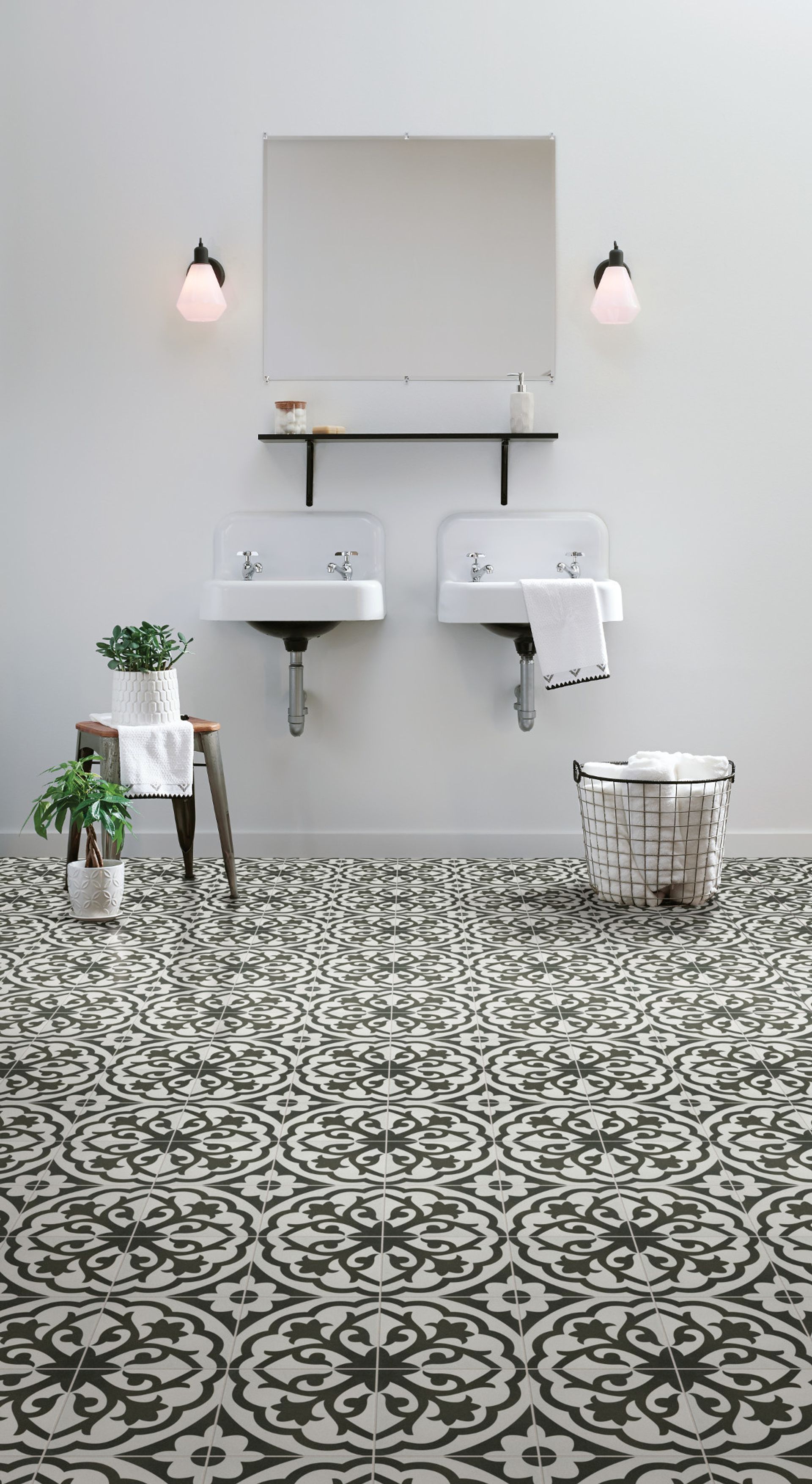 Minimalist bathroom with patterned black-and-white tile, wall sink, mirror, and two sconces.