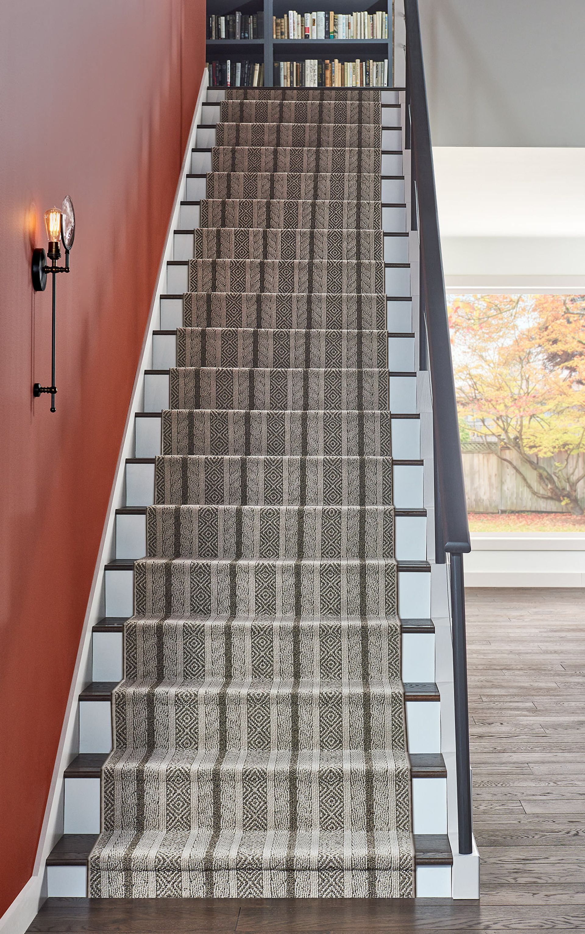 A carpeted staircase with white trim and a red wall, leading to bookshelves at the top.