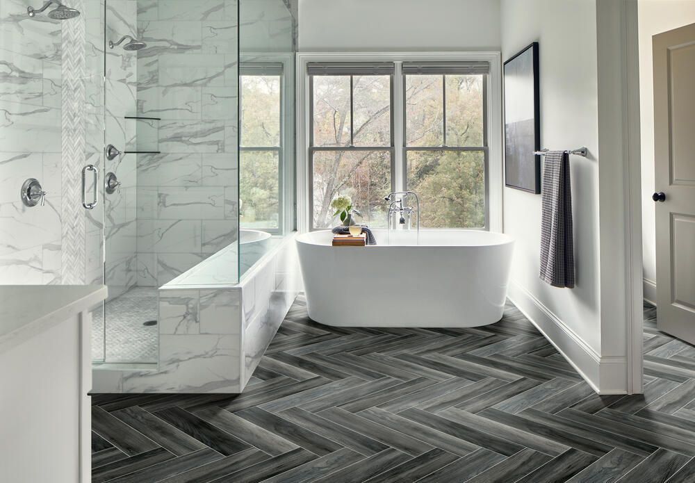 Modern bathroom with freestanding tub, marble shower, and large window overlooking trees
