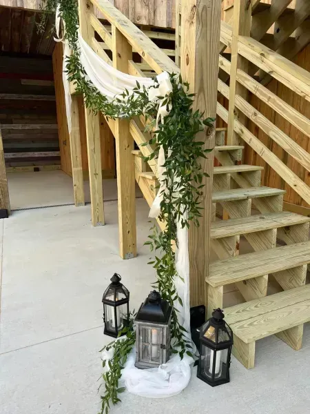 Wooden staircase with a curved railing, green garland, and lanterns arranged on a white cloth below