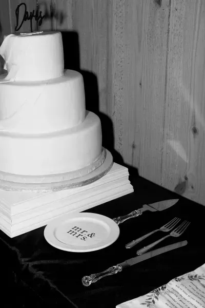 Three-tier white cake on a stand with plates and cake knife on a black tablecloth