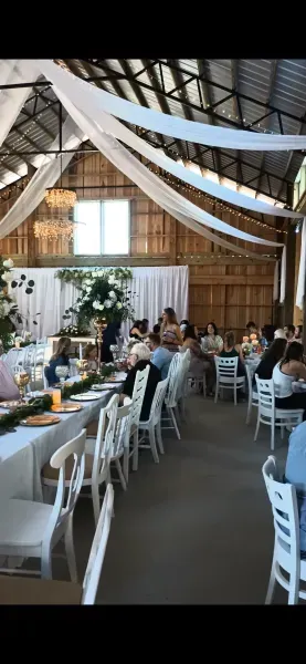 Guests seated at long tables in a rustic barn-style wedding reception venue