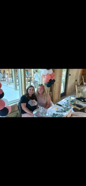 Two people smiling at a decorated table with balloons in a bright party setting