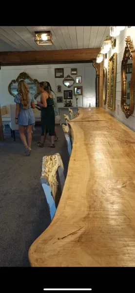 Curving wooden countertop in a rustic room, with two people standing in the background.