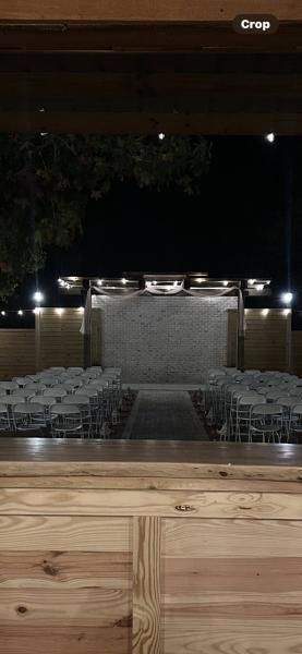 Nighttime outdoor pool or fountain with lit stone steps and water feature beyond a wooden deck.