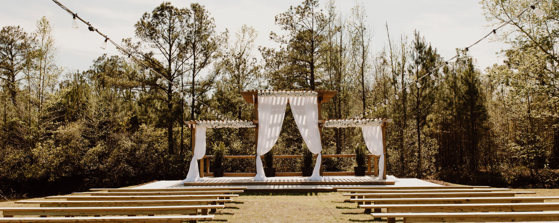 Outdoor wedding altar with white drapes and wooden steps in a wooded clearing