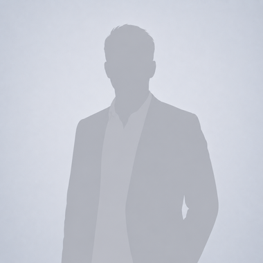 Portrait of a smiling man in a navy blazer and white shirt against a light gray background