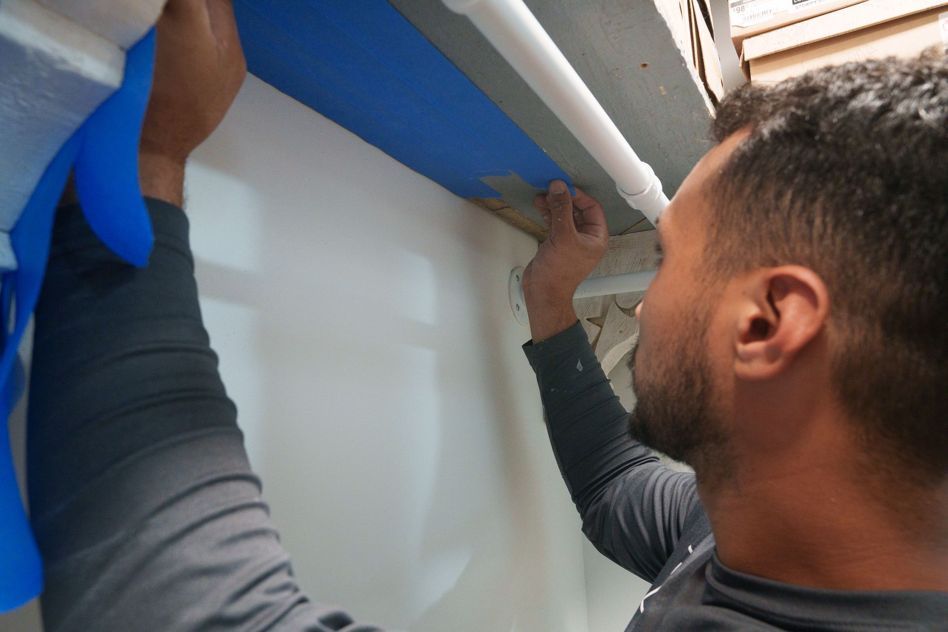 Worker installing blue tape on a wall indoors