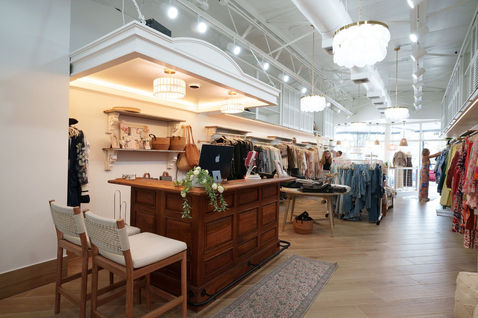 Bright boutique interior with wooden display counters, clothing racks, and white ceiling lights