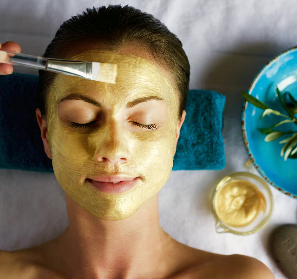 A woman with a yellow mask on her face has a brush on her forehead