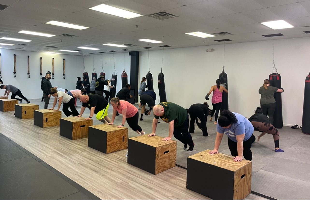 A group of people are doing push ups on wooden boxes in a gym.