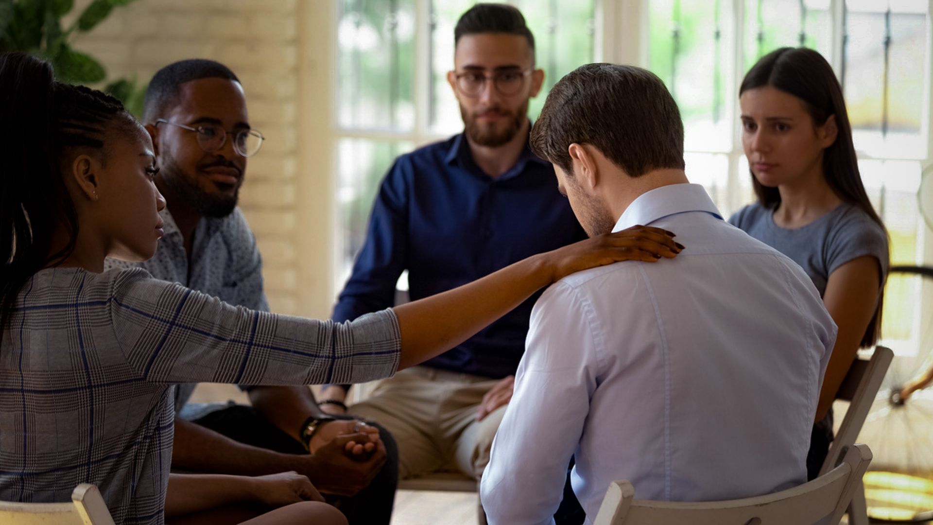 Small group meeting with a person consoling another in a bright room