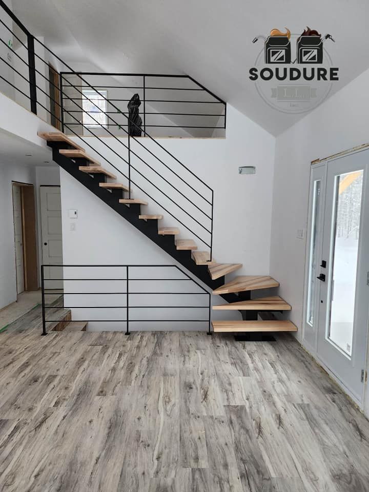 Un escalier en bois avec une rampe en métal dans une pièce avec un plancher en bois.