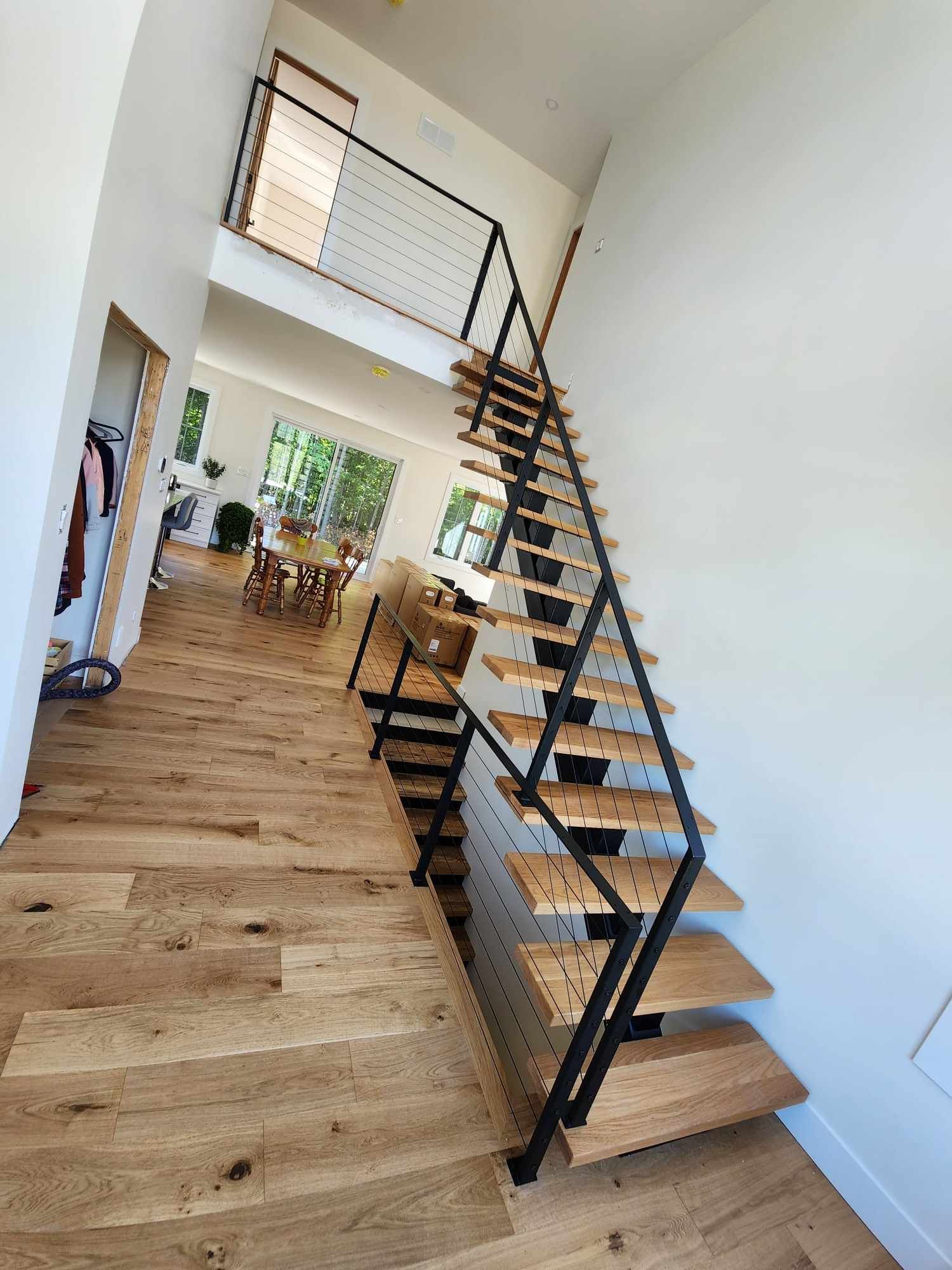 Un escalier en bois avec une rampe noire menant au deuxième étage d'une maison.