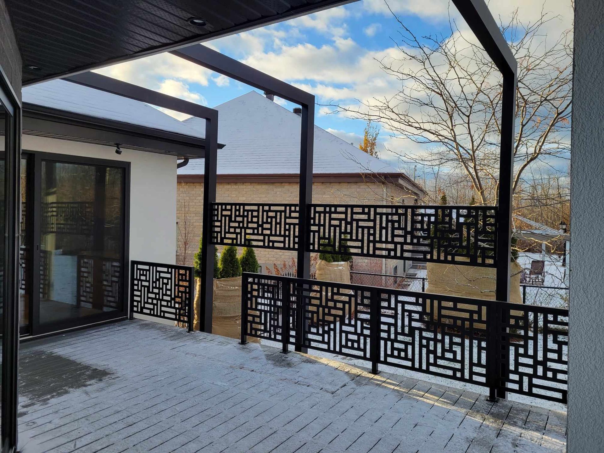 Un balcon avec une clôture et une pergola devant une maison.