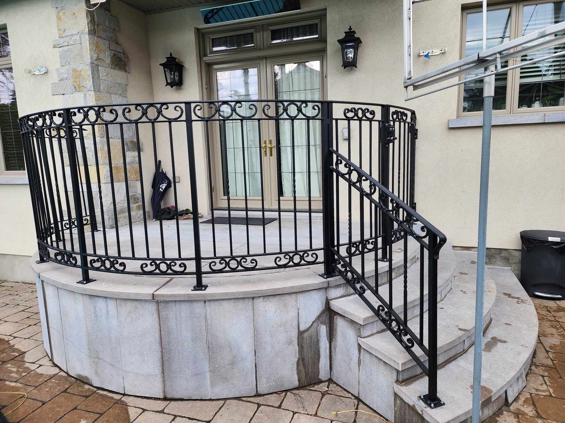 Une balustrade en fer forgé sur un porche avec des escaliers qui y mènent