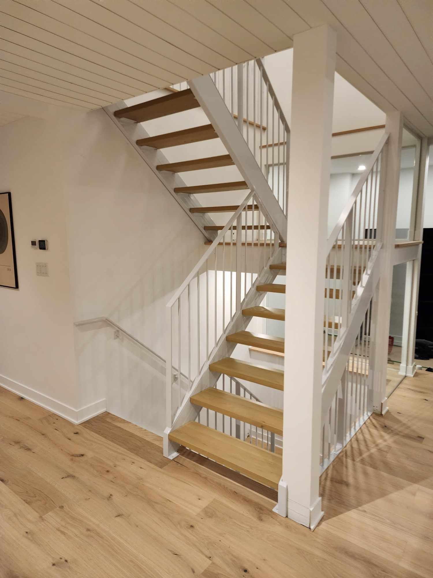 Un escalier avec des marches en bois et une rampe blanche dans une maison.