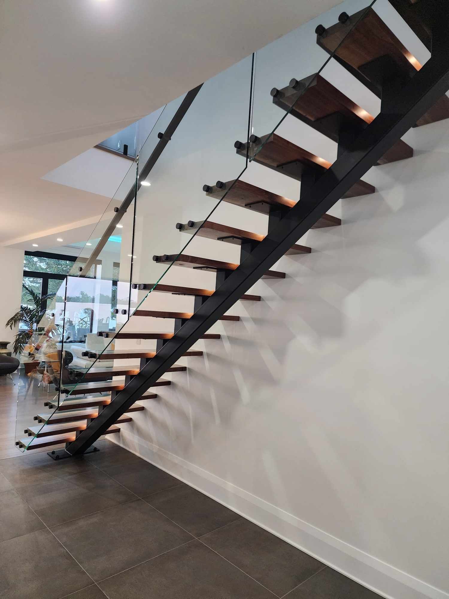 Un escalier avec des marches en bois et une rampe en verre dans une maison.