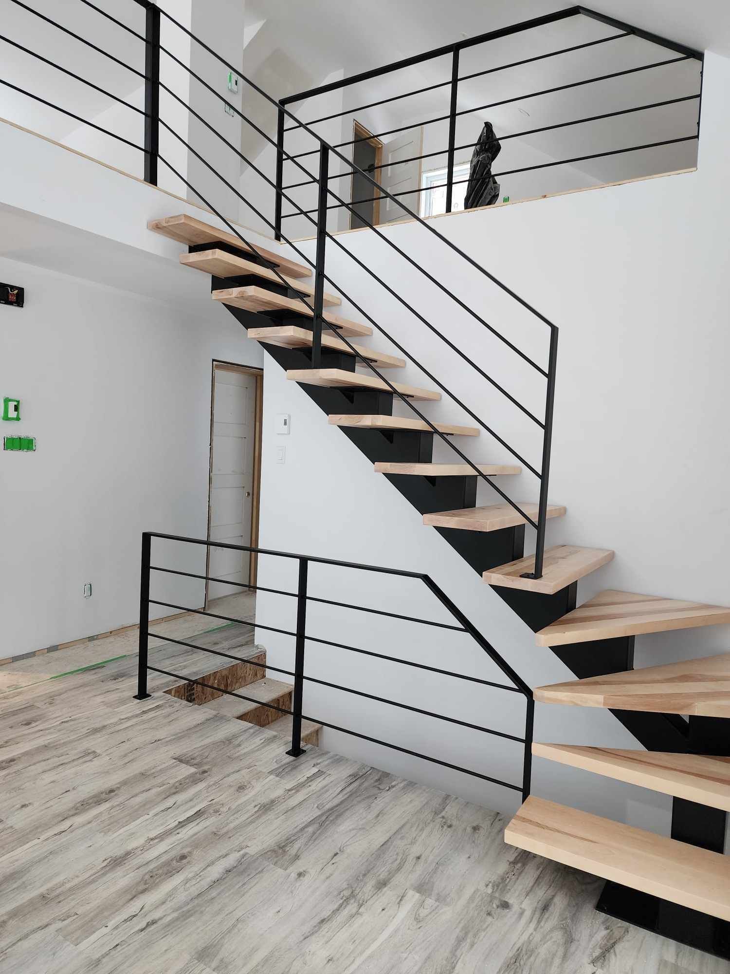 Un escalier avec des marches en bois et une rampe noire