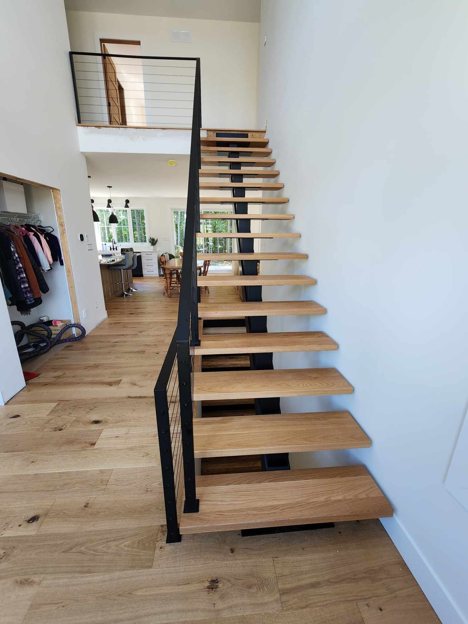 Un escalier en bois avec une rampe en métal dans un couloir menant à un deuxième étage.