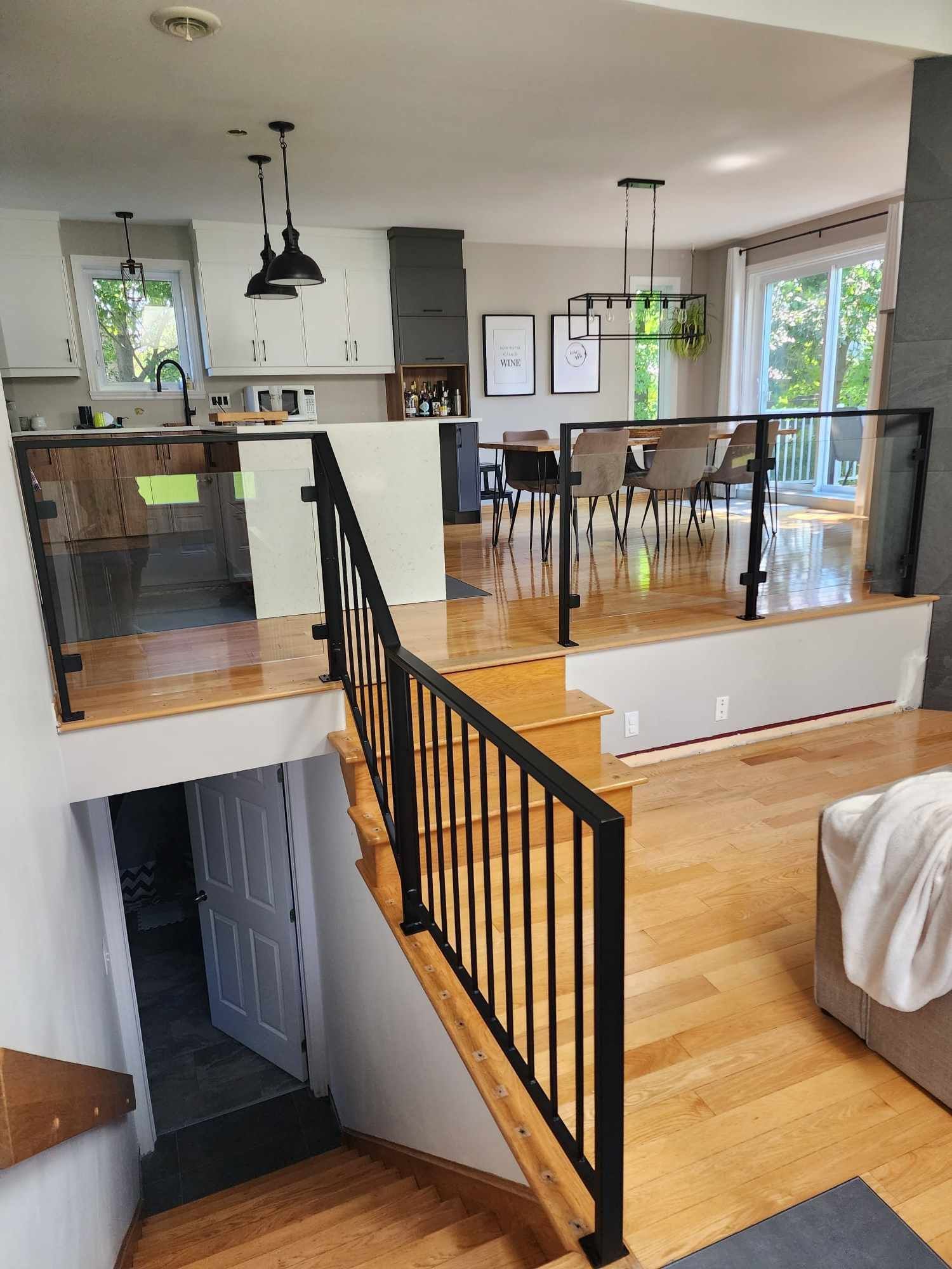 Un salon avec escalier menant à une salle à manger et une cuisine.