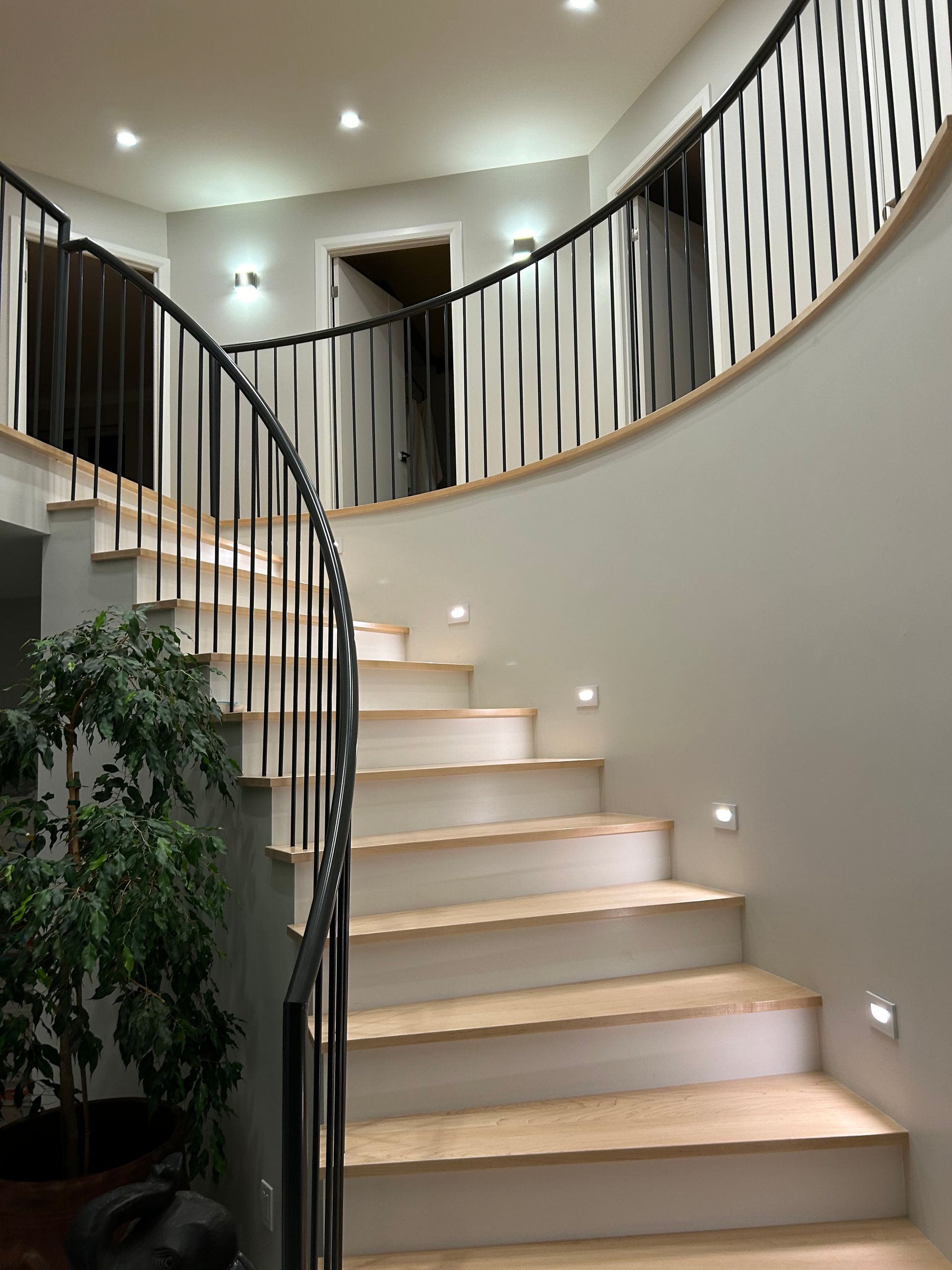 Un escalier courbe avec une rampe en métal et des marches en bois