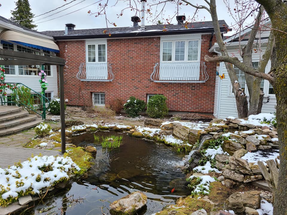 Une maison en briques avec un étang devant.