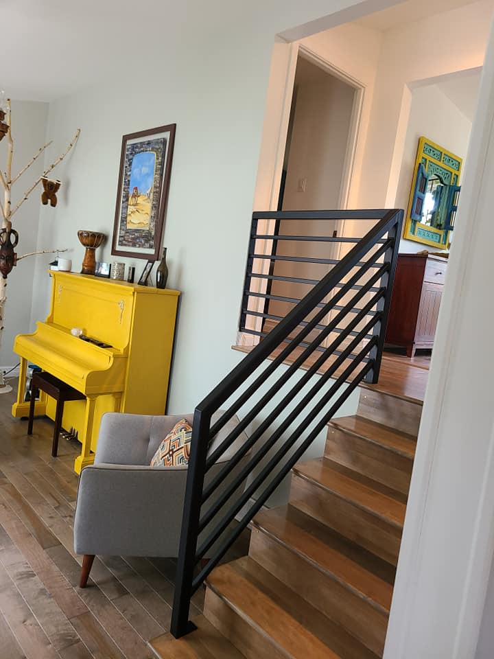 Un salon avec un piano jaune et des escaliers