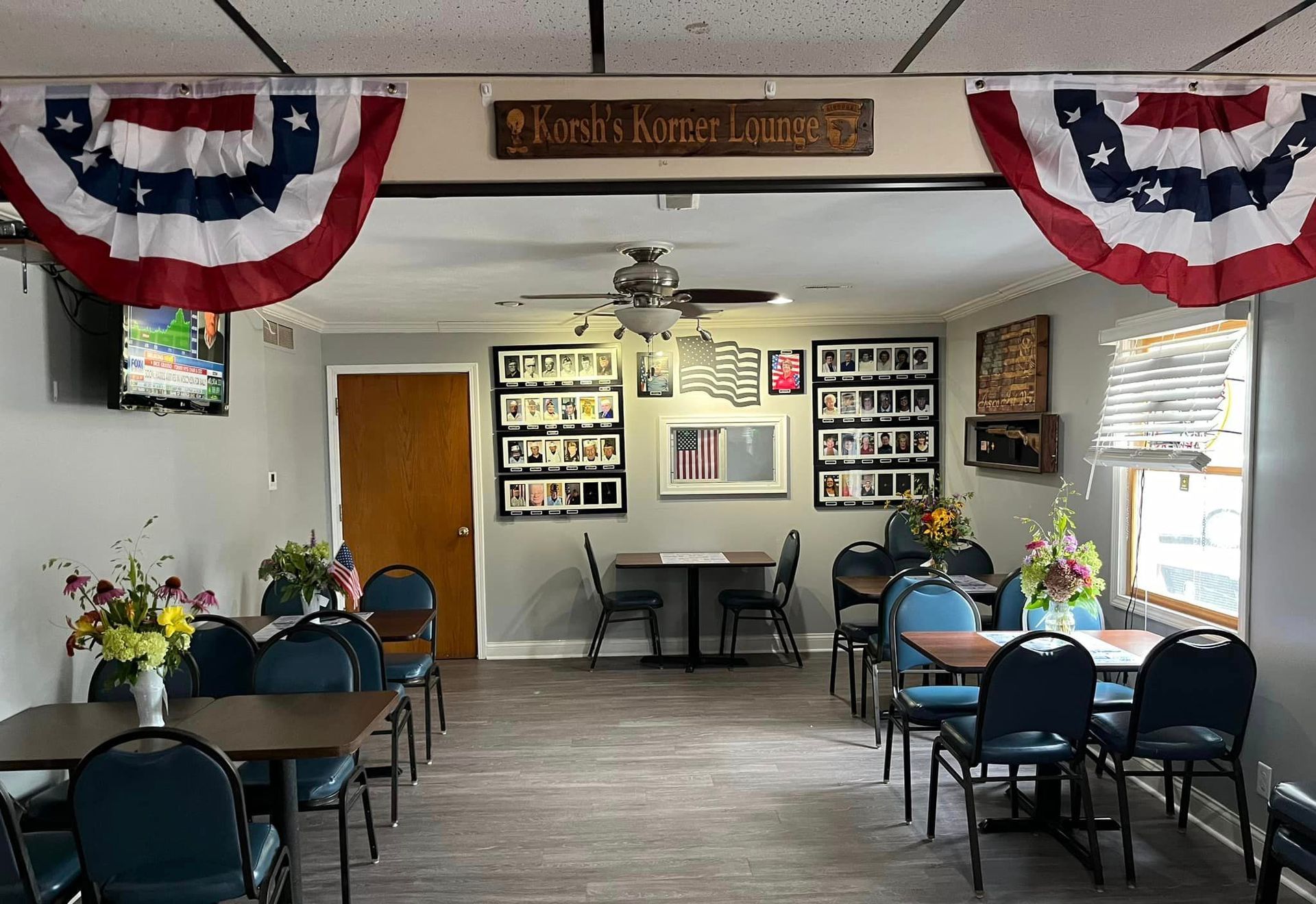 A dining room with tables and chairs and american flags hanging from the ceiling.