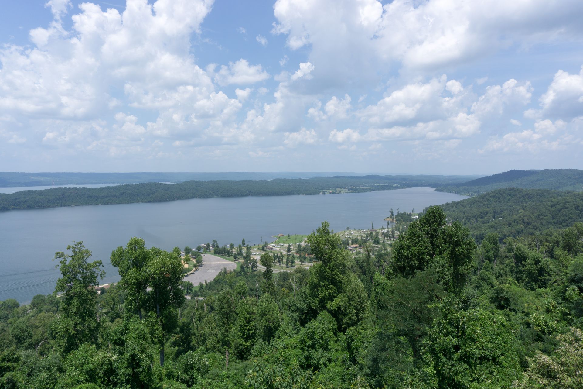 An aerial view of a lake surrounded by trees on a cloudy day.