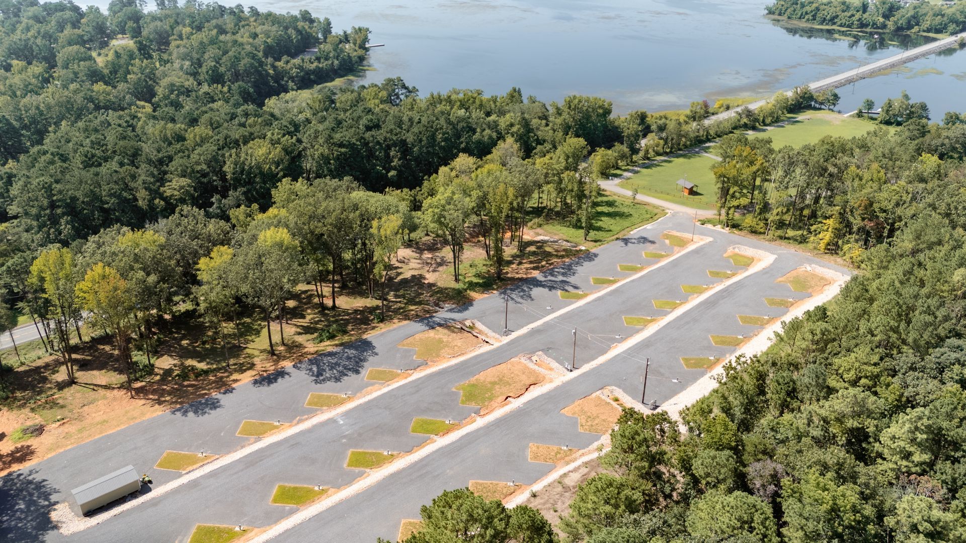 An aerial view of a residential area next to a lake surrounded by trees.