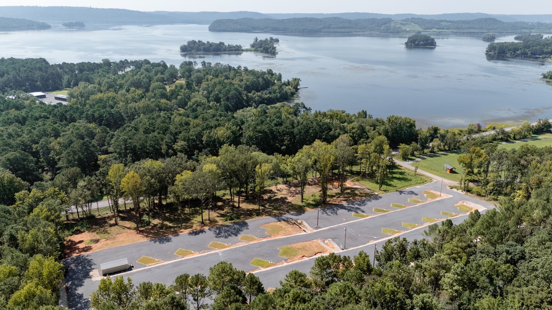 An aerial view of a lake surrounded by trees and a road.