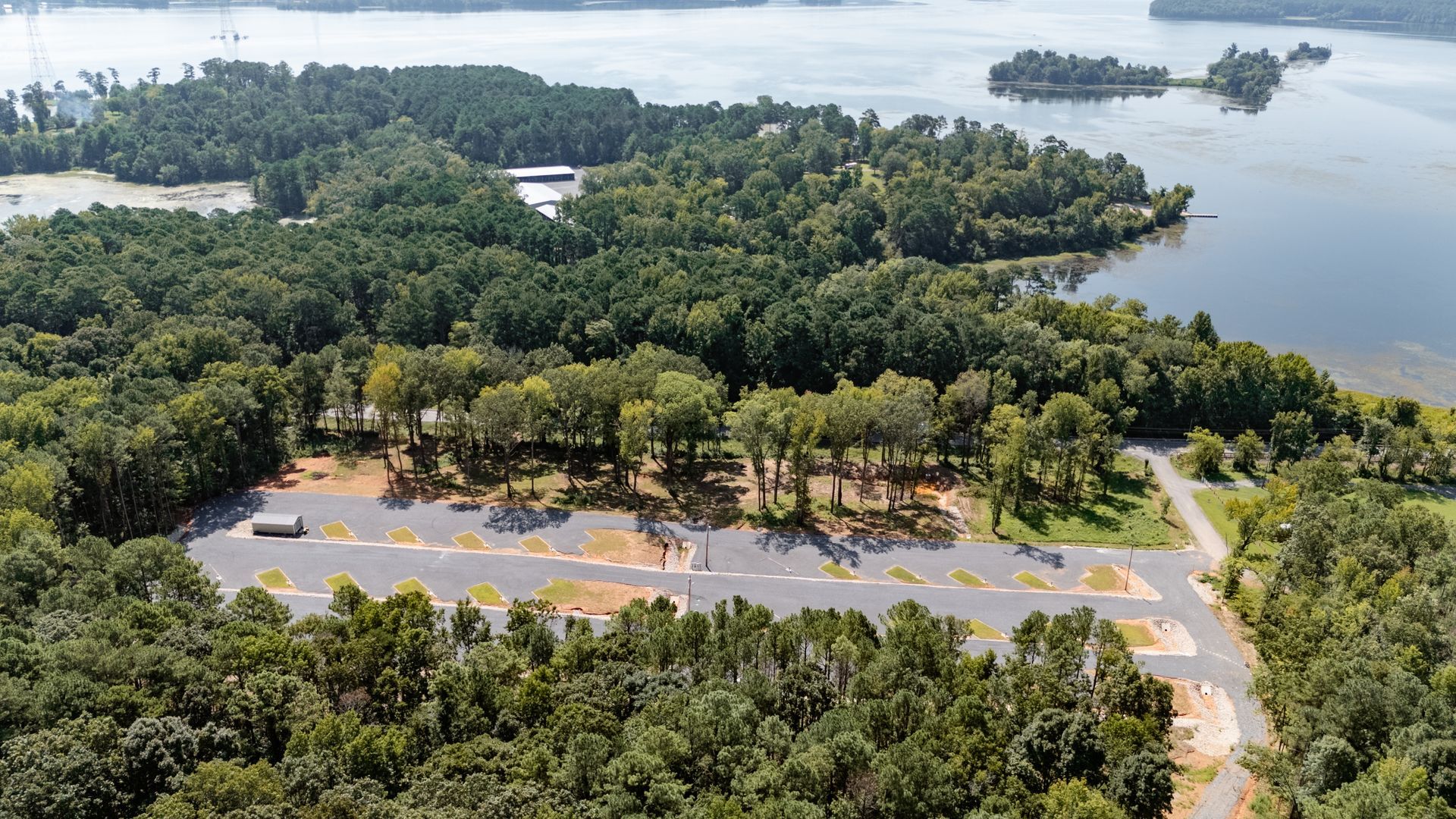 An aerial view of a lake surrounded by trees and a road.