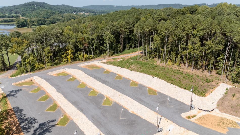 An aerial view of a parking lot surrounded by trees and a lake.