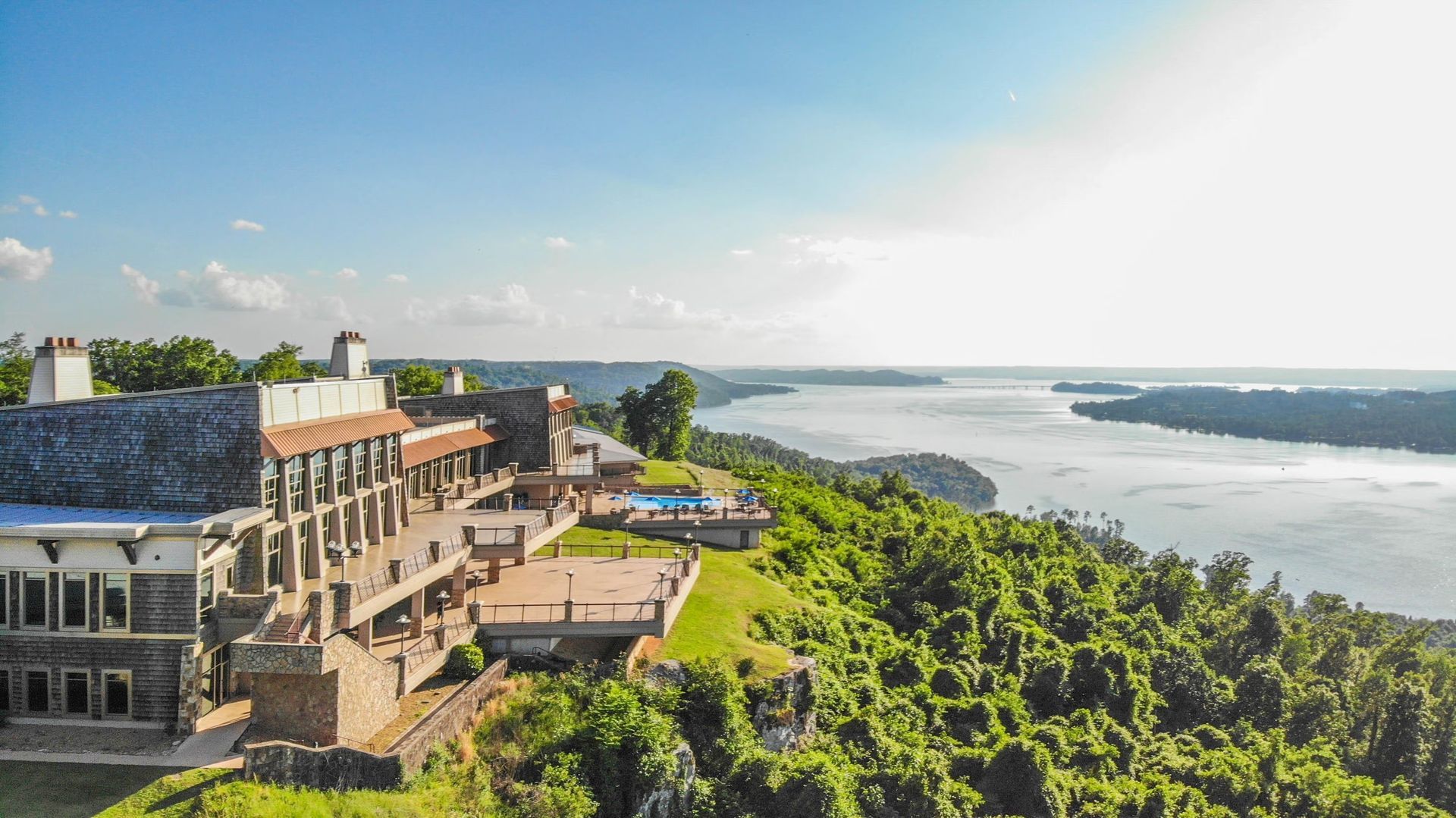 An aerial view of a large building on top of a hill overlooking a river.