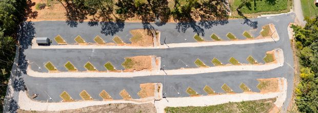 An aerial view of a parking lot with a car parked in the middle.
