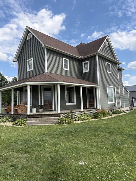 Tan house exterior with white-trimmed windows and a ladder leaning beside them over a grassy lawn