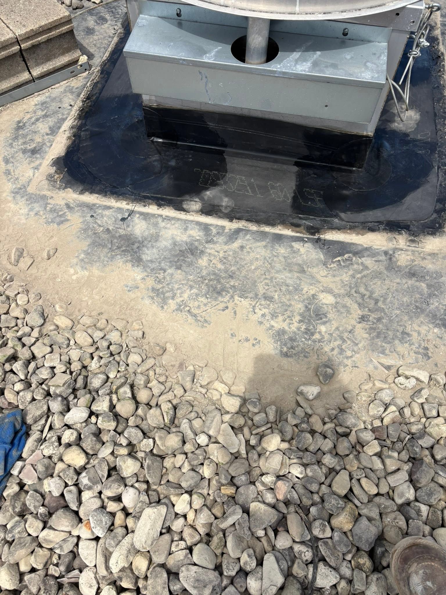 Rooftop HVAC unit on gravel with dark water or tar stains around its base