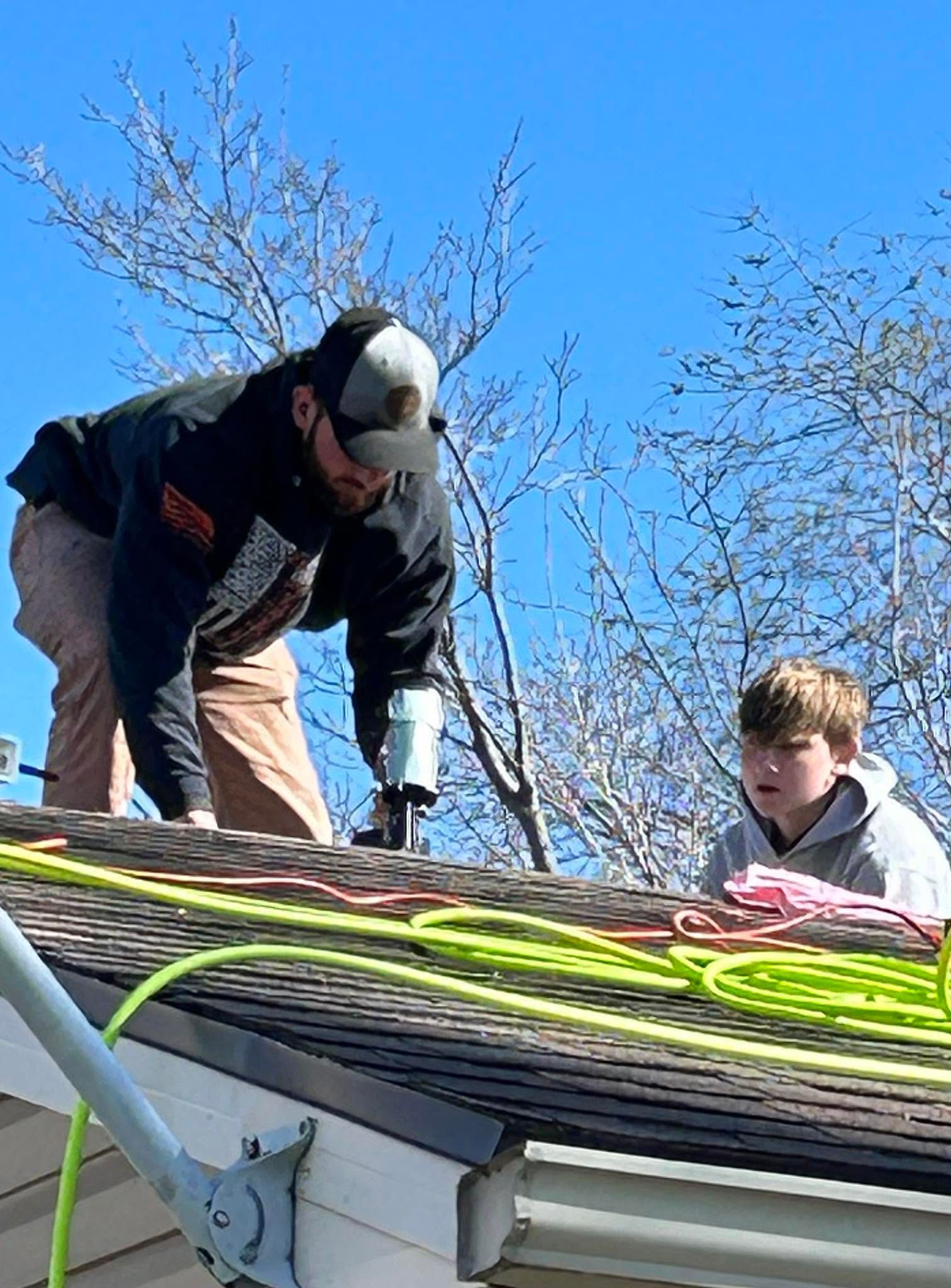 Two workers securing bright ropes on a rooftop under a clear blue sky