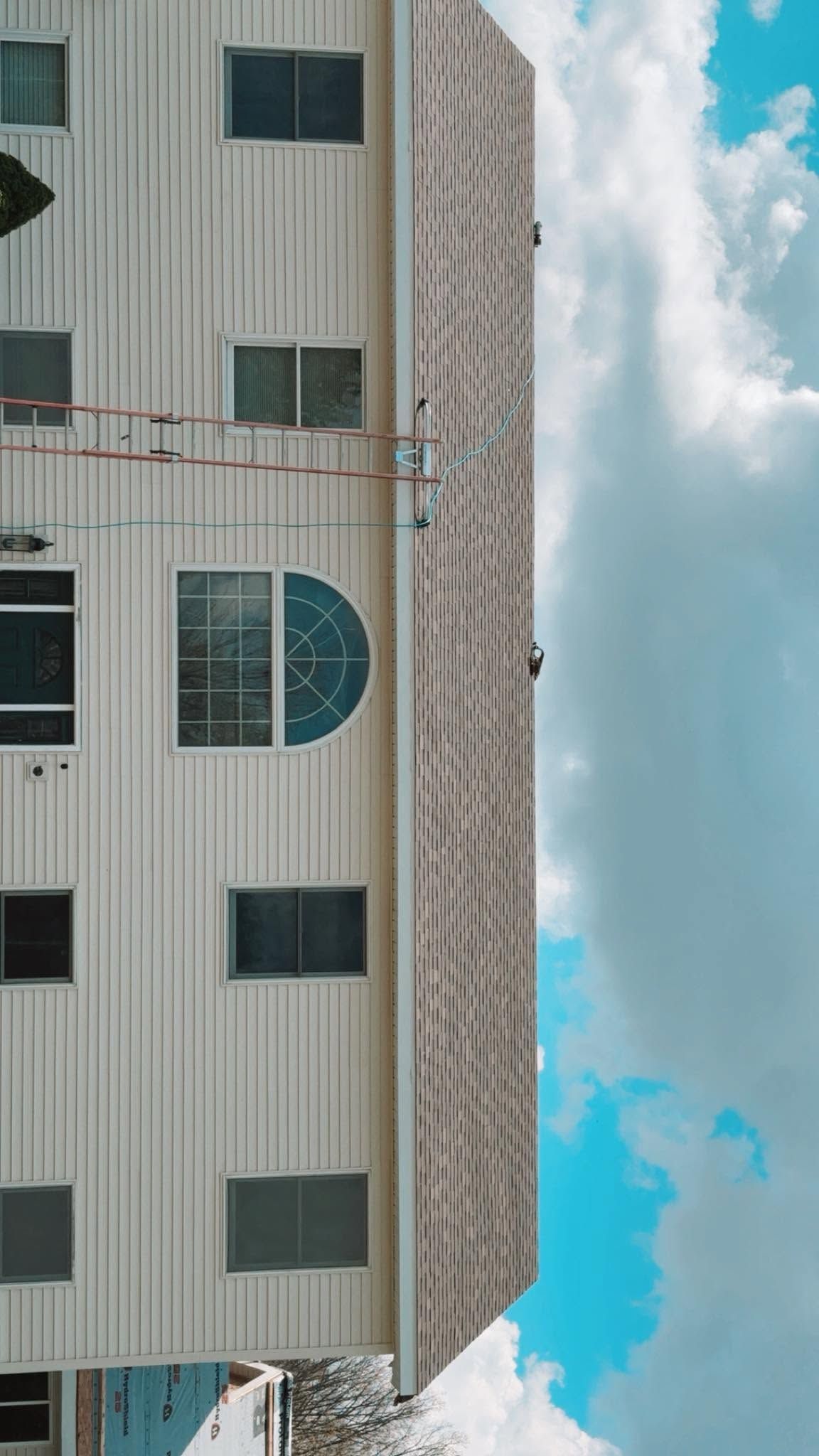 Tall beige apartment building against a bright blue sky with clouds