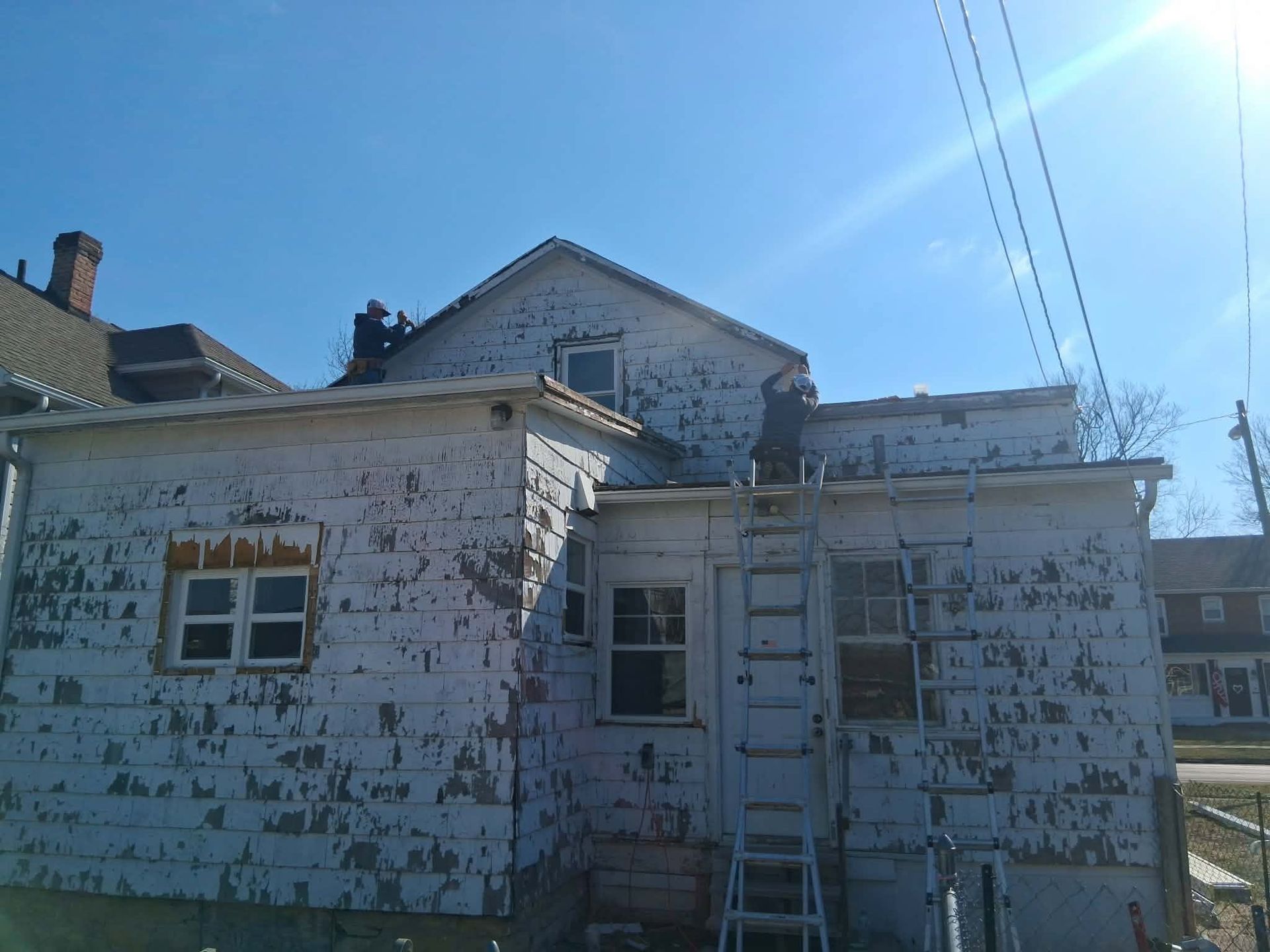 Dilapidated white house with peeling paint under a bright blue sky