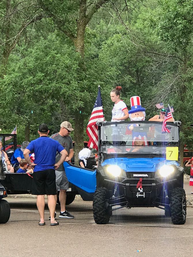 A group of people are standing around a blue atv in a parade.