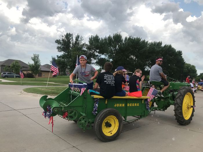 A group of people are riding a john deere tractor in a parade